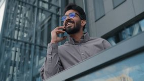 Joyful Indian man talking mobile phone on office terrace outdoors happy smiling Arabian businessman employer ceo executive talk smartphone in city friendly business conversation cellphone call outside - Powered by Shutterstock - Get 15% off with code: PIKWIZARD15