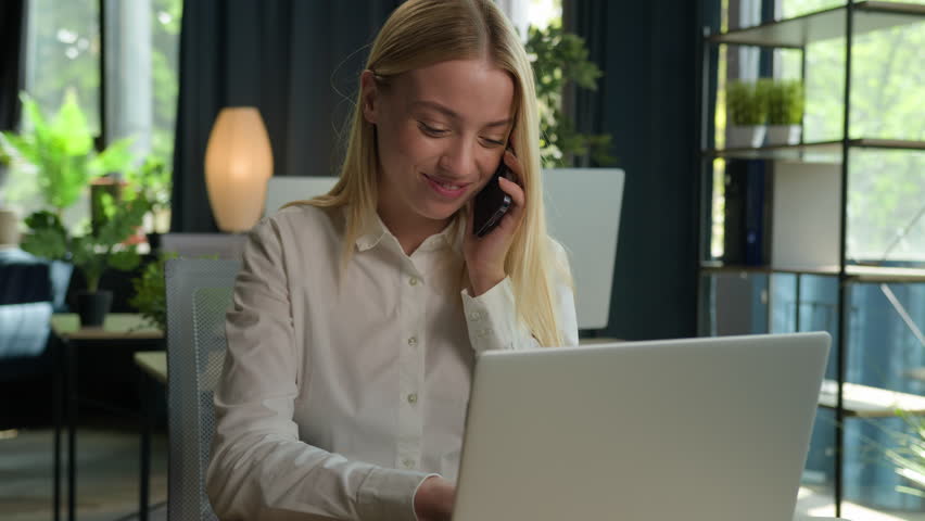 Happy Caucasian businesswoman talk phone conversation consult client business commerce in office smiling woman girl multitask working use laptop check documents on desk support customer mobile call Royalty-Free Stock Footage #1106463757
