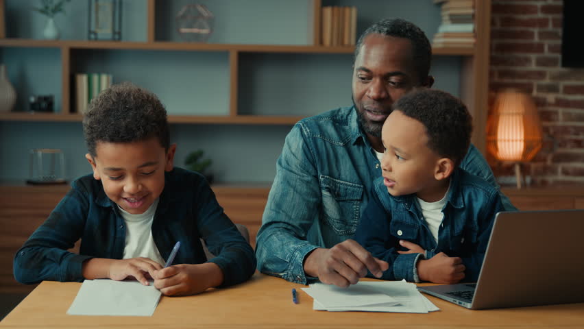 Single parent African American father man babysitter private teacher with two boys kids children help little schoolboy son child boy with school homework teaching writing task distant home education Royalty-Free Stock Footage #1106463769
