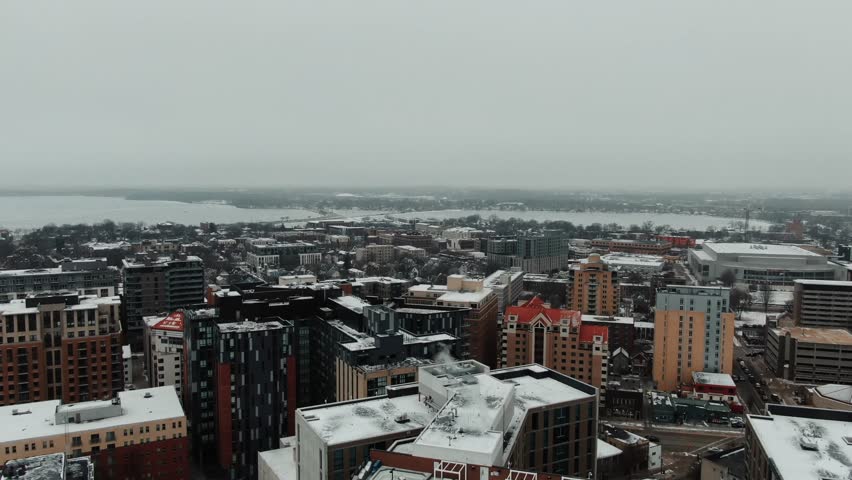 aerial of downtown Madison, Wisconsin in the winter, snow-capped rooflines and Lake Mendota in the distance