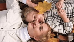 The family has fun in the park. Girl and mother lie on a blanket and fool around. Horizontal video
