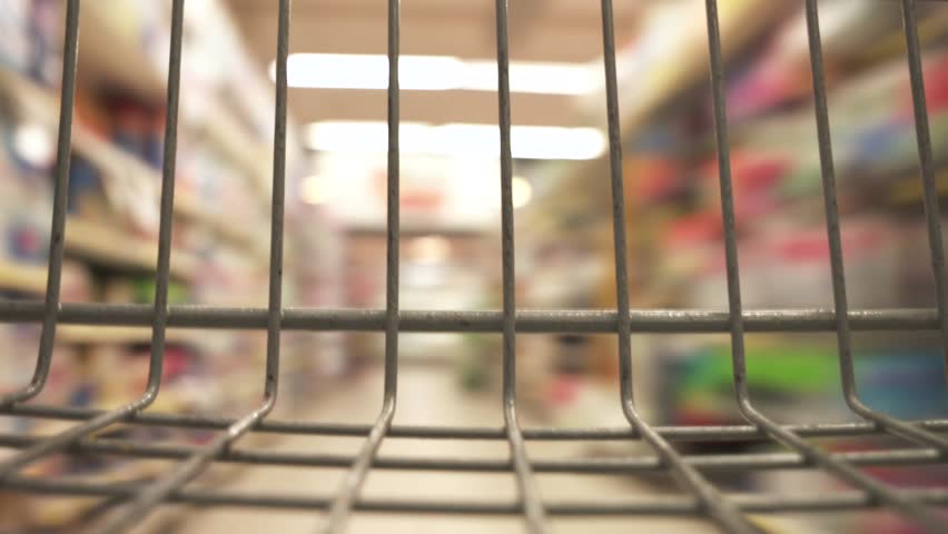 Timelapse close up view from the empty grey shopping cart in a grocery supermarket. Fast motion around the store with blurred background.
