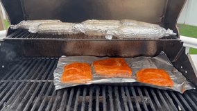 A barbecue with fresh salmon and corn on the cob being cooked on the grill.
