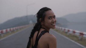 Asian girl turns and smiles on mountain road - Powered by Shutterstock - Get 15% off with code: PIKWIZARD15