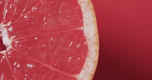 Video of sliced red grapefruit with copy space over red background. Fresh food, fruit and colour concept.