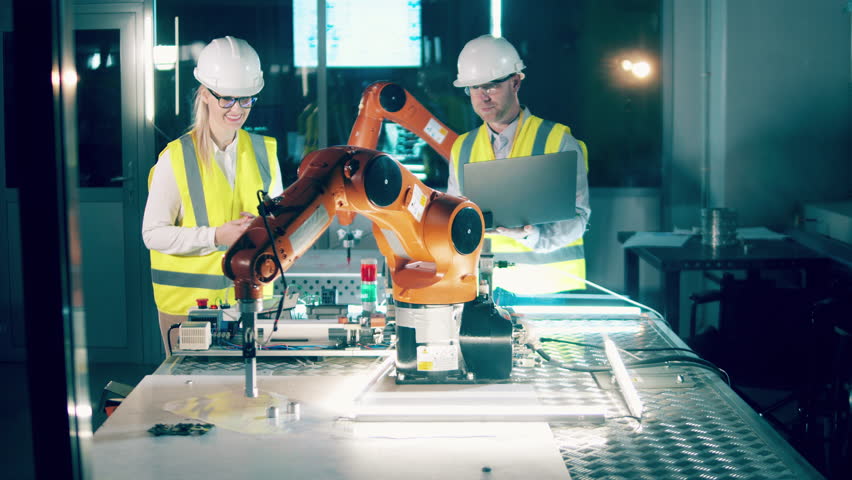 Robotics engineers are observing a robotic arm in modern lab