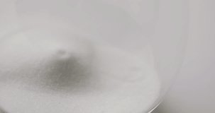 Video of close up of hourglass with sand pouring, copy space on white background. Time and time keeping concept.
