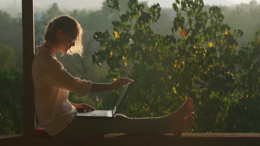 Pretty blonde woman using laptop while sitting on the rooftop in sunlight. Remotely working concept. - Powered by Shutterstock - Get 15% off with code: PIKWIZARD15