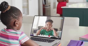 Diverse schoolgirl having laptop video call with biracial schoolboy in slow motion. School, education, technology and online learning.