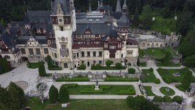 Aerial View of Peles castle in Sinaia, Romania, Trensilvania. Drone video move away. Castelul Peles in  Carpathian forest from fligh.