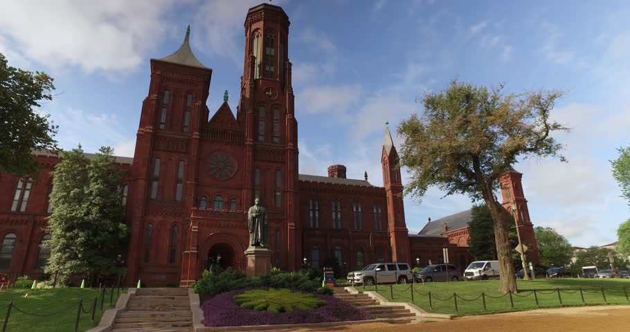 A dolly establishing shot of the red bricked Smithsonian Castle on the Washington Mall in downtown Washington, D.C. on a summer day.  	
