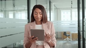 Young busy happy professional African American business woman company manager sales executive wearing suit, holding fintech tab using digital tablet computer standing in office working on pad. - Powered by Shutterstock - Get 15% off with code: PIKWIZARD15