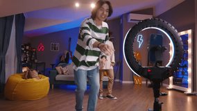 Guys bloggers perform dance challenge. Asian teen guys in cozy home environment create exciting dance video challenge for social media. Dance challenge in social networks. Energy, passion for dancing