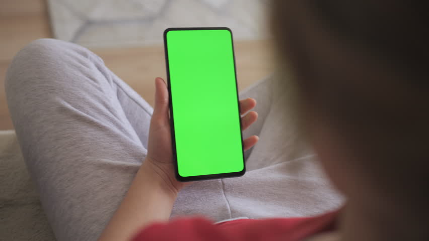 Point of View of Child at Living Room Using Phone With Green Mock-up. Phone With Green Mock-up Screen Chroma Key Surfing Internet Watching Content Videos Blogs Learning. Girl Playing Video Games. Royalty-Free Stock Footage #1106509599