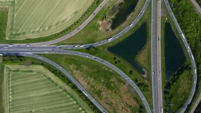 Aerial view of road junction with moving cars. Road interchange or highway intersection. Aerial view, top down view of traffic. Roundabout traffic of cars and trucks on the circle ring road. Vertical.