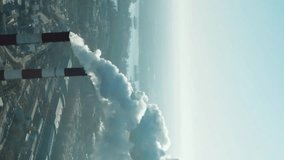 Epic aerial of high smoke stack. Plant pipes pollute atmosphere. Industrial factory pollution, smokestack exhaust gases. Industry zone, thick smoke plumes. Climate change, ecology. Vertical video