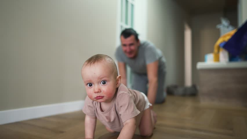 Happy family. Baby crawls on floor with his father. Boy smiles and crawls on floor of house. Dad plays with his son at home. Home kindergarten.Father's day in kindergarten.Happy baby crawling on floor Royalty-Free Stock Footage #1106511575