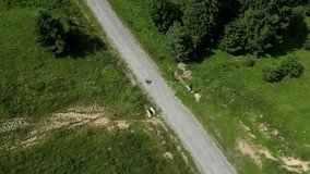 A female cyclist is riding her gravel bicycle on a gravel road between mountains.Sport cycling motivation drone video.