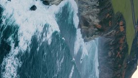 Road along the coast drone view. Travel by car. The sea coast and the road.USA, Monterey, California. Aerial view of a road running between a mountain and the ocean waves. Vertical video. 