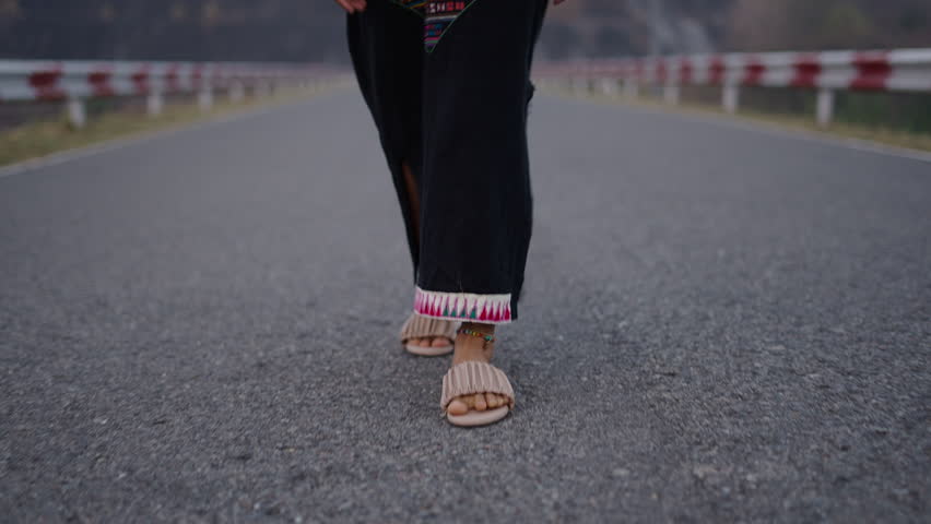 Womens feet walk along a mountain road in Asia
