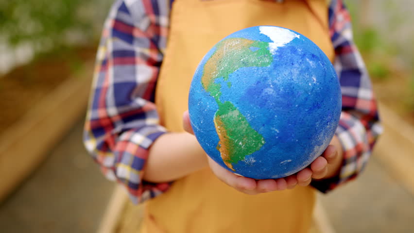 Preschooler in yellow apron calling for ecosystem protection holds model of Earth Royalty-Free Stock Footage #1106533647