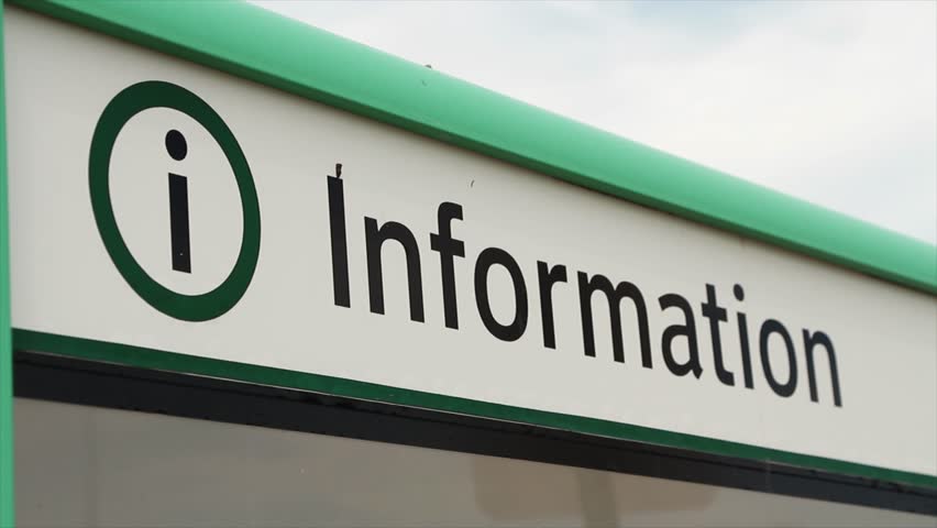 close on the caption information in black writing on a white background, green border on top, letter i in a circle next to it, with an empty glass bulletin board beneath it, shot on angle