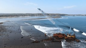Aerial view of abandoned offshore construction crane over sea shore near the beach of Nusa Lembongan, an island close to Bali, Indonesia. 4K drone footage video