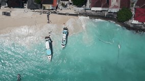 Aerial shoreline view of jetty at Jungut Batu Village in Nusa Lembongan with tourist speedboat anchored on the beach. Travel destinations close to Bali island, Indonesia. 4K drone footage video
