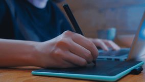 Designer hand drawing illustration on a tablet. Modern professions in design. Close-up hand with pen working on laptop. Woman painting in digital in neon cyan green light of computer screen at home. - Powered by Shutterstock - Get 15% off with code: PIKWIZARD15