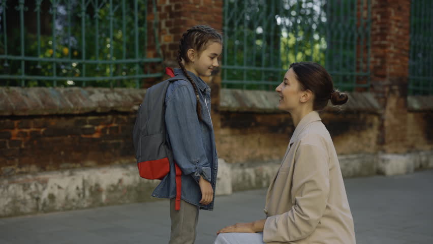 Happy mother escorts child to school. Kid happy dream concept. Girl rushes to lesson back to school. Positive girl talk to mom and hug her. Morning before the school Royalty-Free Stock Footage #1106545389