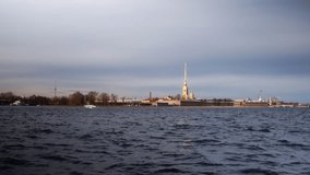 Peter and Paul Fortress in St. Petersburg, Russia. The golden spire of the cathedral, the fortified stone walls, the flag of the Russian Navy. View from the Neva River on a sunny day. High quality 4k