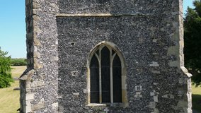 A crawling boom-shot of the tower of St Mary's church in Chartham, showing one of the large windows and clock.