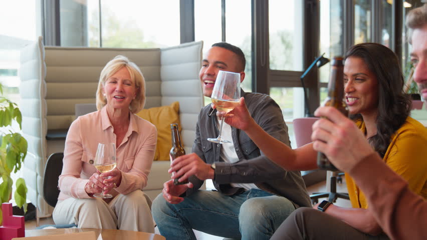 Staff at informal meeting in office making a toast with wine and beer at after work drinks - shot in slow motion Royalty-Free Stock Footage #1106553845