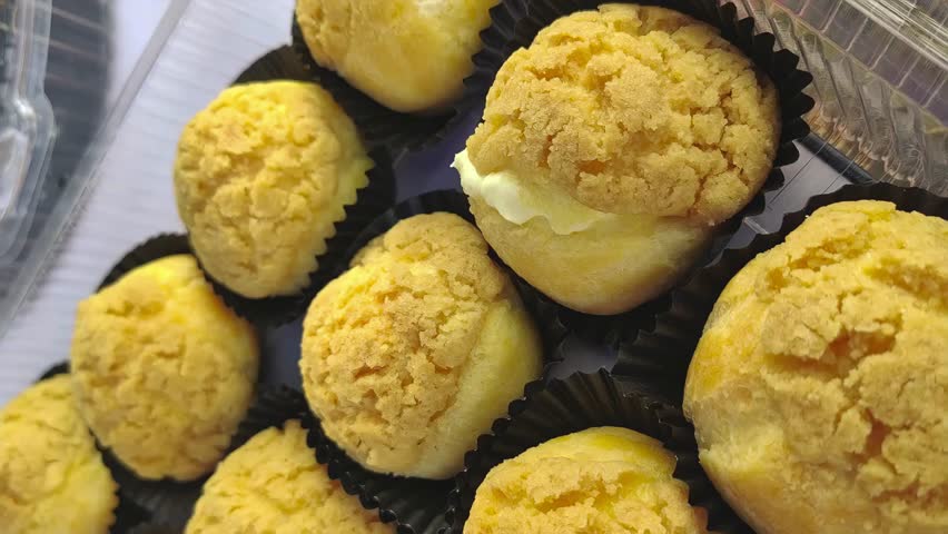 Eclairs, cream puffs, and cheesecake in plastic containers. 4K vertical video.