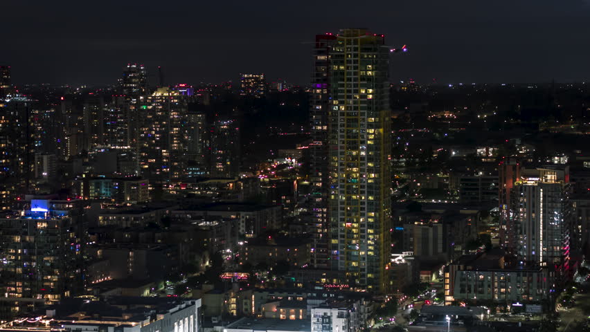 Establishing Aerial View Shot of San Diego CA, California, United States of America, downtown at night evening, East Village, tracking left, passenger plane approaching for landing