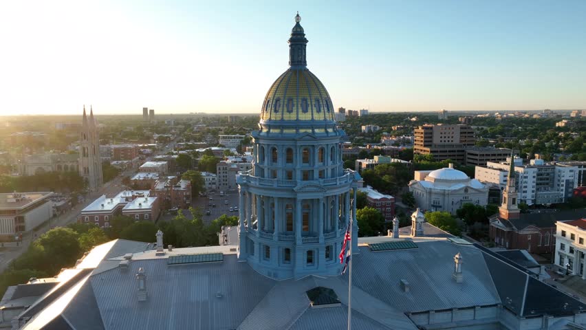 Aerial orbit around capitol building dome in Denver, Colorado. Beautiful sunshine during sunrise in CO. American flag and Colorado flag on government building in Denver, the capital city.