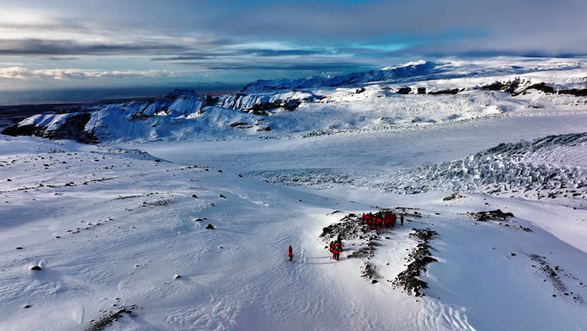 Aerial view of people looking at the Myrdalsjokull glacier panorama, after riding snowmobiles in Iceland, at dusk