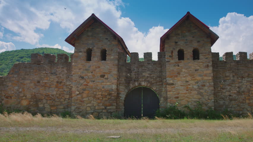 Roman soldier with a spear walking near a wall of a military fort. Dolly shot and slow motion