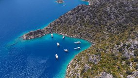 Excursion boats take a swimming break in Aquarium Bay, Kekova in Turkey. Aerial of motorboats on azure sea in summer. A beautiful turquoise bay and Blue Voyage yachts. Cinematic flying over drone shot - Powered by Shutterstock - Get 15% off with code: PIKWIZARD15