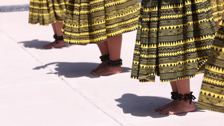 Hula dancers wearing kukui nut anklets take one step forward