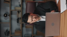 Middle-aged asian man in formal wear closing lid of portable computer with disappointment in office. Unhappy business person receiving shocking e-mail about losing important deal. Vertical video.