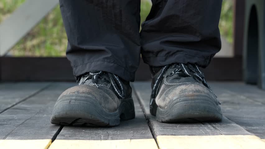 close up of men feet in old worn shoes marching on the spot on the wooden flooring. relaxing on a sunny summer day in the countryside.
