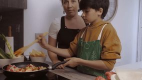 A child with an apron on cooks in a frying pan - Videos of parents cooking with their children at home.