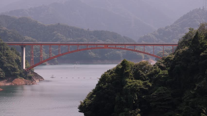 A view of the lake with a large red arch bridge. Taken at Miyagase Dam.