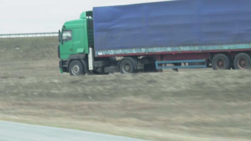 A truck with a semi-trailer is driving along the highway. Transportation of heavy loads. Axle load. Slow motion