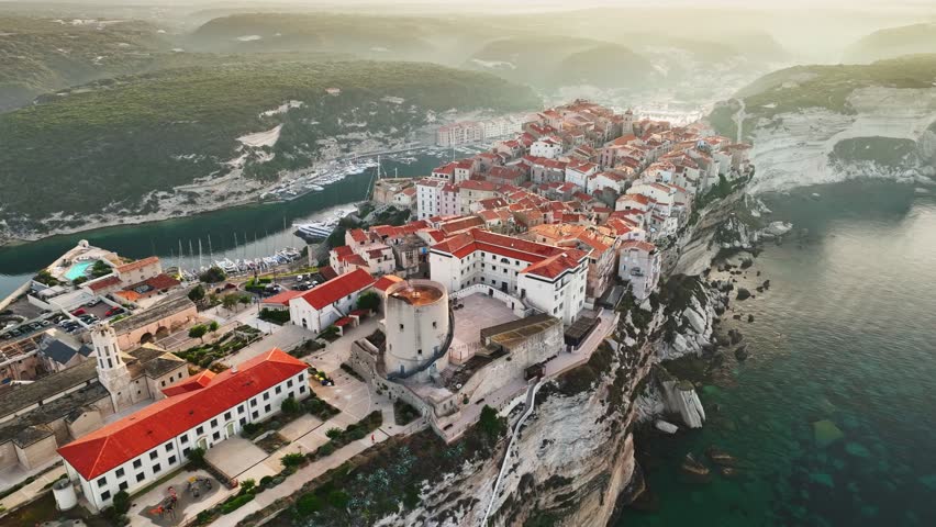 Aerial morning view of Bonifacio, Corsica island. Houses on cliff in the rays of rising sun in Bonifacio old town, Corsica, France. Mediterranean sea Royalty-Free Stock Footage #1106599433