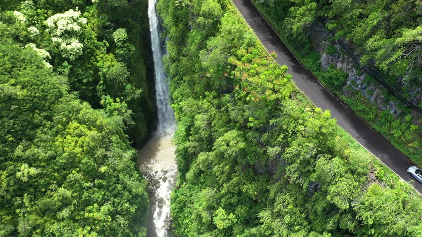 An aerial footage of a waterfall and an asphalt road to Hana in Maui, Hawaii