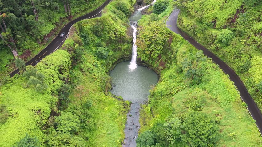 An aerial footage of a waterfall and an asphalt road to Hana in Maui, Hawaii