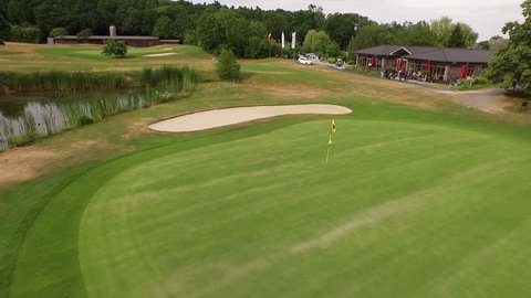 Bad Homburg, Germany – June/28/2015: Aerial perspective of a golf player on Germany picking up two golf balls with his golf club on a sunny day.