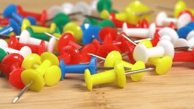 Colorful push pins rotating on the table macro. Drawing pins for marking on the map of the Earth or city. Plastic pins